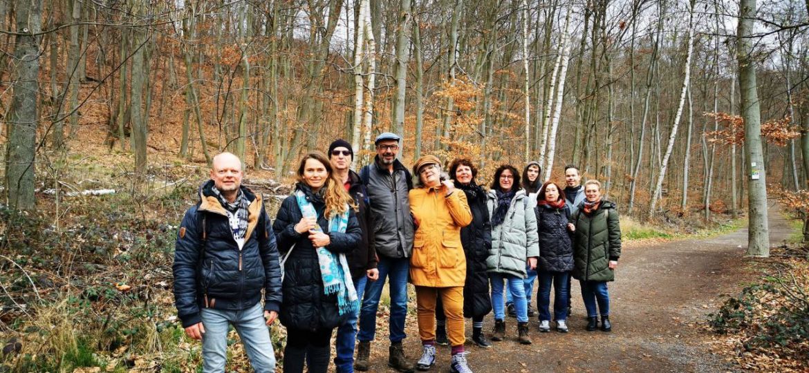 Eine Gruppe von Menschen im März 2023 im Wald mit Bäumen, die noch keine Blätter haben im Wald am Maria Laacher See
